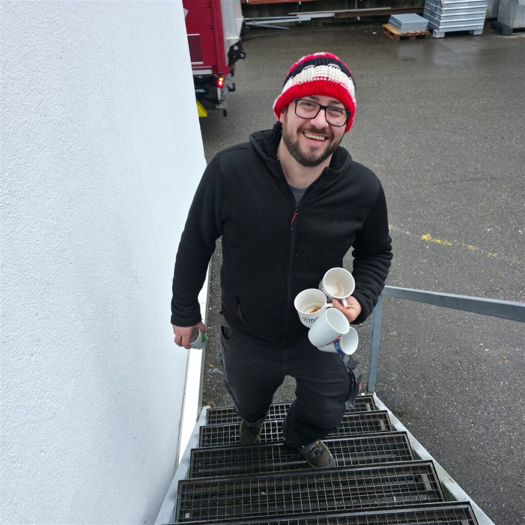 Franko Brinz von FraBriK trägt fünf Kaffeetassen eine Treppe hinauf